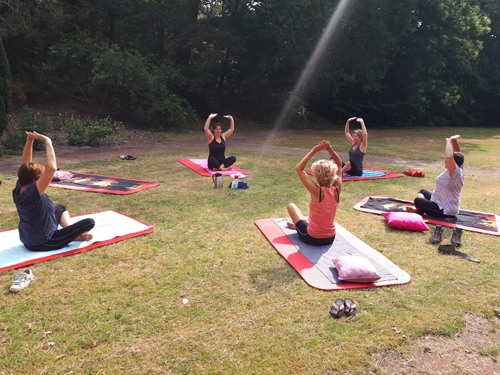 Een groep in yoga poses in een circel in de buitenlucht